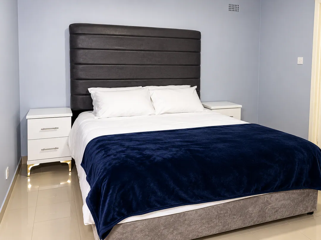 Contemporary guest bedroom with a padded headboard, crisp white linen and a navy throw