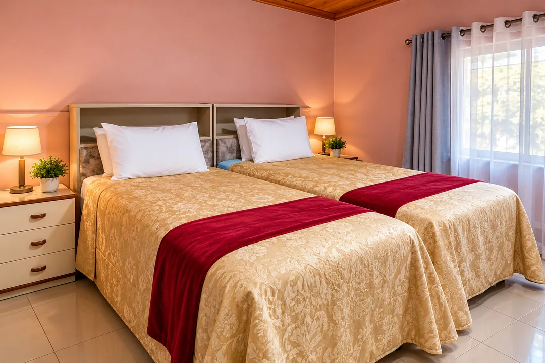 Guest room with two single beds, gold bedspreads and red runners beside bedside lamps