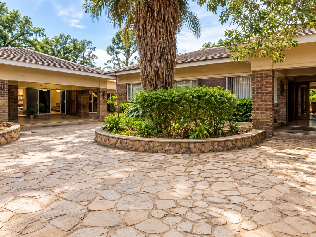 Paved courtyard with a circular stone planter and palm tree in front of the lodge's brick buildings
